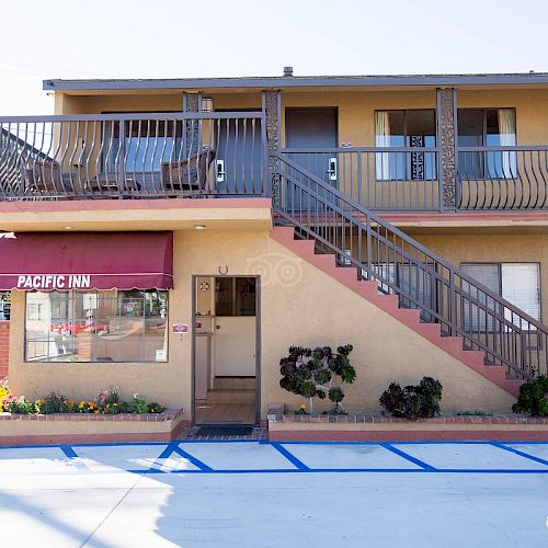 A two-story motel with a staircase, red canopy labeled 