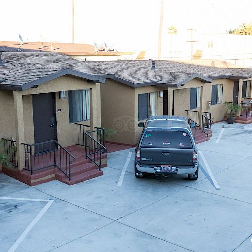 A row of single-story motel rooms with a car parked in front, concrete parking area, potted plants, and a TripAdvisor watermark on the image.