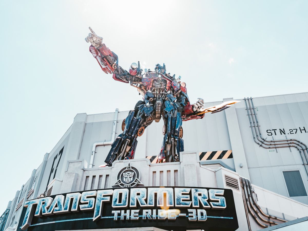 A large Transformers statue stands atop a building with the sign 